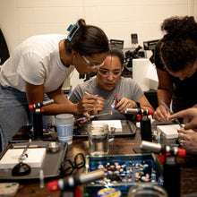 Load image into Gallery viewer, Three people wear safety glasses while learning jewelry design and silversmithing at a Halie & Co. workshop.