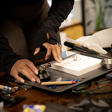 Load image into Gallery viewer, A person uses small metal tools to assemble a gemstone ring in a jewelry design and silversmithing workshop.