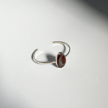 Load image into Gallery viewer, The Botswana Agate Cuff | Size 5.5 showcases a round, brown Botswana agate gemstone set in a sterling silver open cuff. Elegantly displayed on a white surface with soft gray shadows, this handmade bracelet highlights the unique beauty of the agate centerpiece.