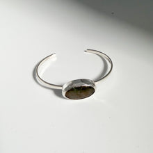 Load image into Gallery viewer, This stunning handmade jewelry piece, the “Labradorite Cuff | Size 6,” features an elegant sterling silver bracelet with an oval dark labradorite stone centerpiece, displayed gracefully on a white surface.